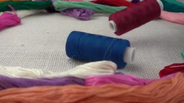 Renkli küf ipliklerinin arka planına karşı çuval bezi üzerine çok renkli makaralar dökülüyor. Yavaş çekim.