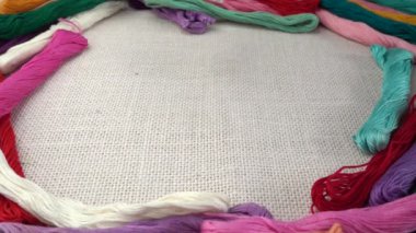 Renkli küf ipliklerinin arka planına karşı çuval bezi üzerine çok renkli makaralar dökülüyor. Yavaş çekim.