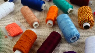 Renkli küf ipliklerinin ve çuval bezi arka planında izole edilmiş çok renkli makaraların üst görünümü.