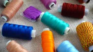 Renkli küf ipliklerinin ve çuval bezi arka planında izole edilmiş çok renkli makaraların üst görünümü.