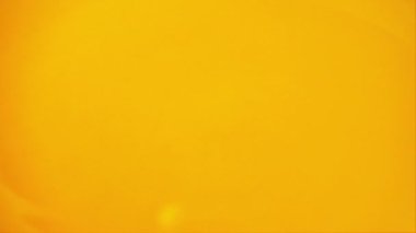 Meyve suyunun yüzeyine bir damla portakal suyu düşer. Yavaş çekim.