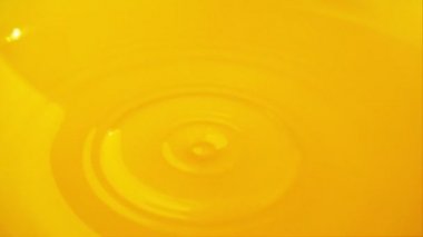 Meyve suyunun yüzeyine bir damla portakal suyu düşer. Yavaş çekim.