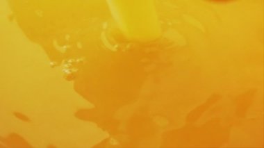 Portakal suyu dökmek ve sıçratmak. Portakal dilimleri meyve suyuna dökülüyor. Yavaş çekim.