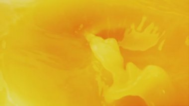 Portakal suyu dökmek ve sıçratmak. Portakal dilimleri meyve suyuna dökülüyor. Yavaş çekim.