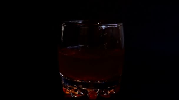 孤立した黒の背景にウイスキーグラスに氷のキューブを落下 スローモーション — ストック動画