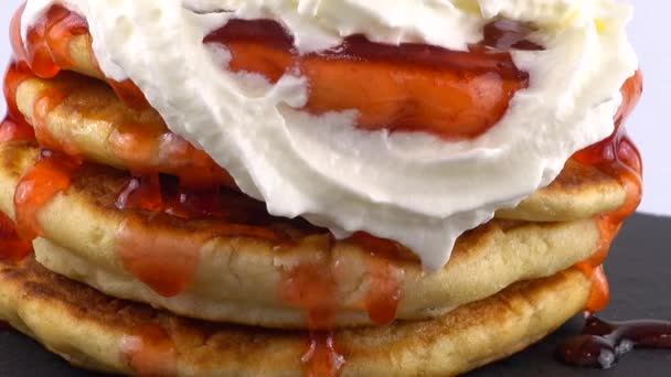 覆有草莓和奶油的松饼 背景为白色 煎饼躺在一块黑色的圆石板上 — 图库视频影像