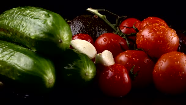 Körsbärstomater Gurkor Vitlök Avokado Och Röd Lök Svart Bakgrund Vattendroppar — Stockvideo