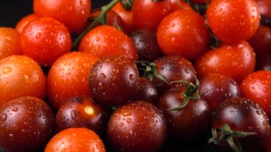 Su damlalarında siyah arkaplanda vişne domatesleri.