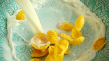 Mısır gevrekleri bir süt püskürtüsüyle bir tabağa düşer. Yavaş çekim.