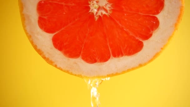 Water Stroomt Naar Beneden Uit Een Schijfje Grapefruit Een Oranje — Stockvideo