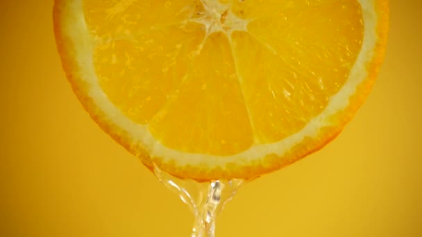 オレンジの背景にあるオレンジのスライスから水が流れ落ちます スローモーション — ストック動画