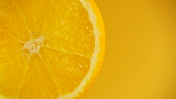 オレンジの背景にあるオレンジのスライスから水が流れ落ちます スローモーション — ストック動画