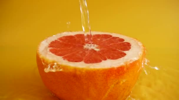 Mitad Pomelo Chorro Agua Sobre Fondo Naranja Movimiento Lento — Vídeo de stock