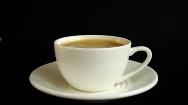 Siyah arka planda bir fincan kahveye şeker düşmesi. Yavaş çekim.