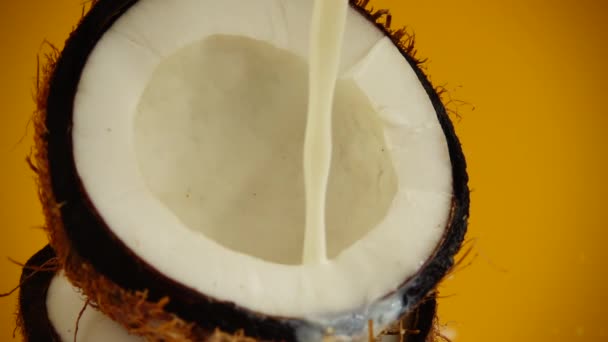 オレンジの背景にココナッツミルクのスプラッシュ スローモーション — ストック動画