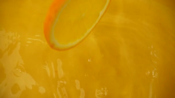 Sinaasappelschijfjes Vallen Het Water Een Oranje Achtergrond Langzame Beweging — Stockvideo
