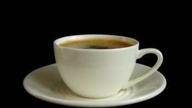 Siyah arka planda bir fincan kahveye şeker düşmesi. Yavaş çekim.
