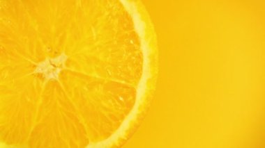 Turuncu arka plandaki bir dilim limondan su akar..