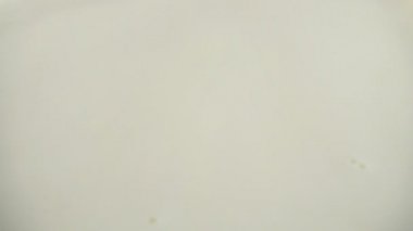 Sütlü yüzeye bir damla süt düşer. Yavaş çekim.