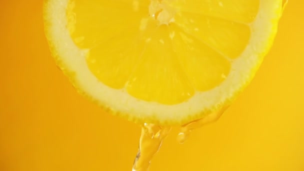 Wasser Fließt Von Einer Zitronenscheibe Auf Orangefarbenem Hintergrund Herab — Stockvideo