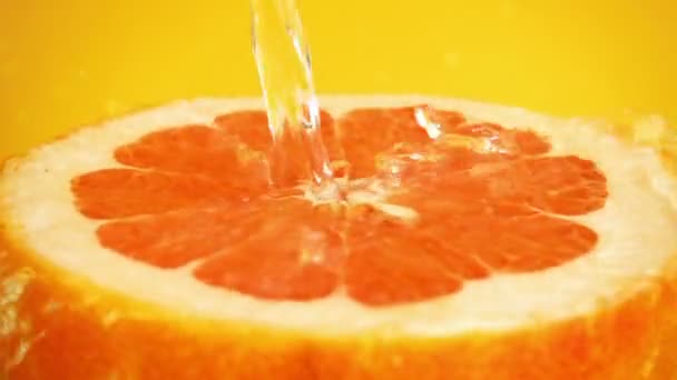 Mitad Pomelo Chorro Agua Sobre Fondo Naranja Movimiento Lento — Vídeo de stock