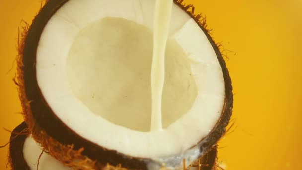 Spritzer Milch Einer Kokosnuss Auf Orangefarbenem Hintergrund Zeitlupe — Stockvideo
