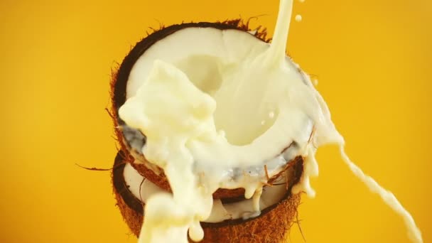 Een Scheutje Melk Een Kokosnoot Een Oranje Achtergrond Langzame Beweging — Stockvideo