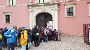 WARSAW, POLAND - APRIL 26, 2022: Groups of schoolchildren waiting for the start of excursions to the Royal Castle of Warsaw.