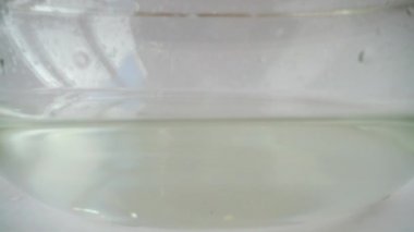 Domatesler cam bir kase suya düşer. Yavaş çekim.