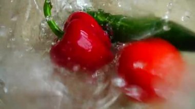 Domates, salatalık ve tatlı kırmızı biber cam bir kase suya düşer. Yavaş çekim.