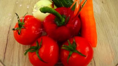 Domates, kırmızı biber, soğan, salatalık ve havuç cam kasede suyla yıkanır. Yavaş çekim.
