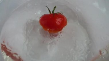Cam bir kase suya düşen domatesler. Yavaş çekim.
