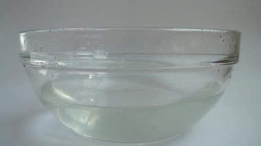 Falling cucumbers in a glass bowl of water. Slow motion.