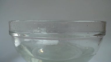 Falling zucchini into a glass bowl of water. Slow motion.