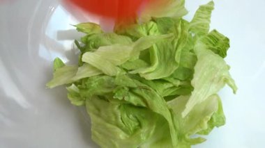 Preparing salad in a glass bowl. Falling lettuce leaves, tomatoes, cucumbers, sweet peppers, olives and bryndza and feta cheese.