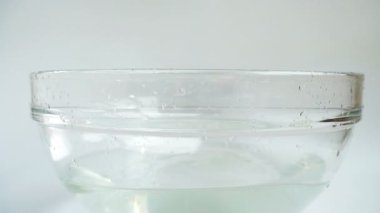 Falling zucchini into a glass bowl of water. Slow motion.