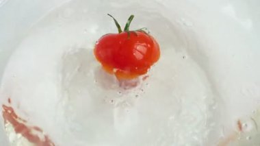 Cam bir kase suya düşen domatesler. Yavaş çekim.