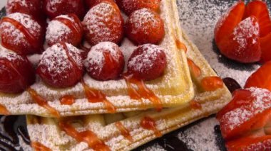 Çilekli Belçika waffleları, tatlı çilek sosu ve taş tahtada pudra şekeri..