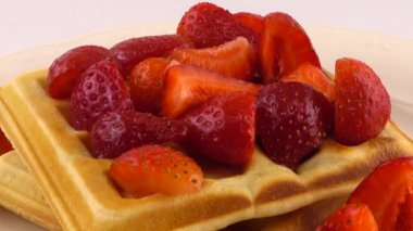 Beyaz arka planda bir tabakta çilek ve pudra şekerli Belçika waffleları..