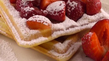 Çilekli Belçika waffleları, krema ve pudra şekerli beyaz bir arka planda..