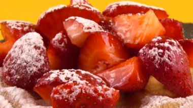 Çilekli Belçika waffle 'ları ve turuncu arka planda taş bir tahtada pudra şekeri..