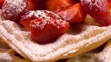 Çilekli Belçika waffle 'ları ve turuncu arka planda taş bir tahtada pudra şekeri..