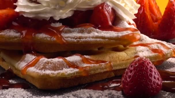 比利时华夫饼 带有草莓 甜草莓 奶油和糖粉 背景为橙色的石板 — 图库视频影像