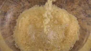 Pirinç, suyla dolu cam bir kaseye dökülür. Yavaş çekim.