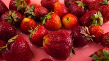 Çileklerin üzerine su damlaları düşer. Yavaş çekim.