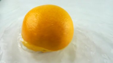 Beyaz bir zemin üzerinde olgun greyfurt şeklinde suyla dönüyor. Yavaş çekim.