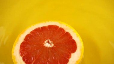 Turuncu bir arka planda olgun ve sulu greyfurt parçaları. Yavaş çekim.