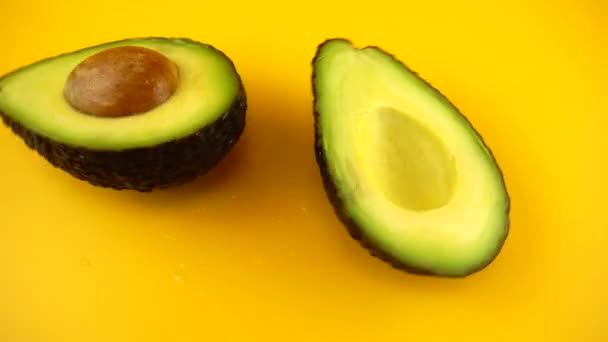 Roterende Segmenten Van Een Rijpe Sappige Avocado Een Oranje Achtergrond — Stockvideo