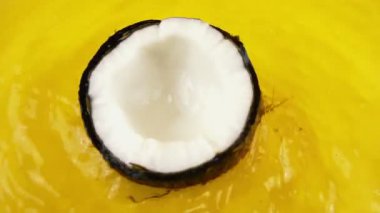 Turuncu bir arka planda olgun ve sulu hindistan cevizinin dönüşümlü bölümleri. Yavaş çekim.