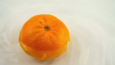 Beyaz bir zemin üzerinde olgun turuncuyu suyla döndürüyor. Yavaş çekim.